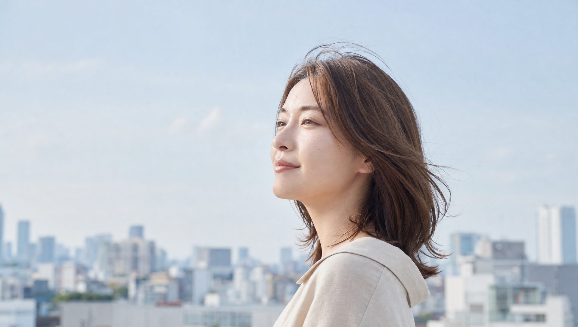 都会の屋上で遠くを見る女性